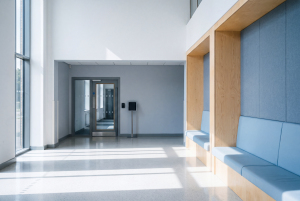 An empty British academy entrance hall with a secure inner door, card reader and signing-in screen, where supplier self-certification is checked on arrival rather than assumed.