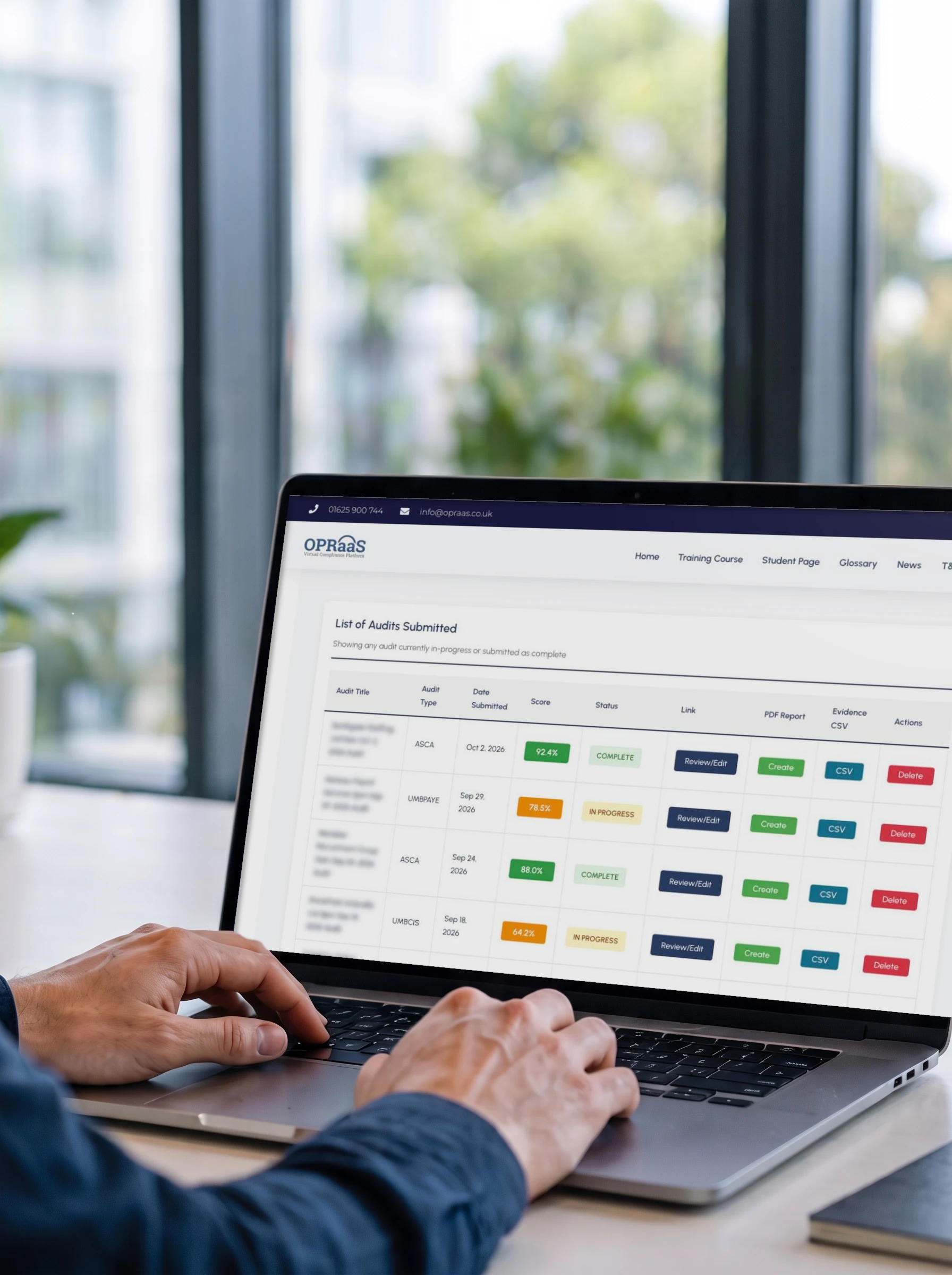 Hands on a laptop showing the OPRaaS Audit Platform list of audits submitted, with scores and status